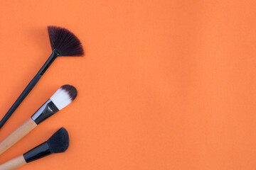 Makeup brush and cosmetics on colorful backgrounds