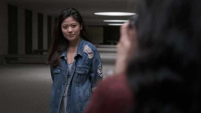 Young asian woman posing to the camera while someone taking a photo to her.