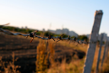 Barbed wire poles in a field near the city