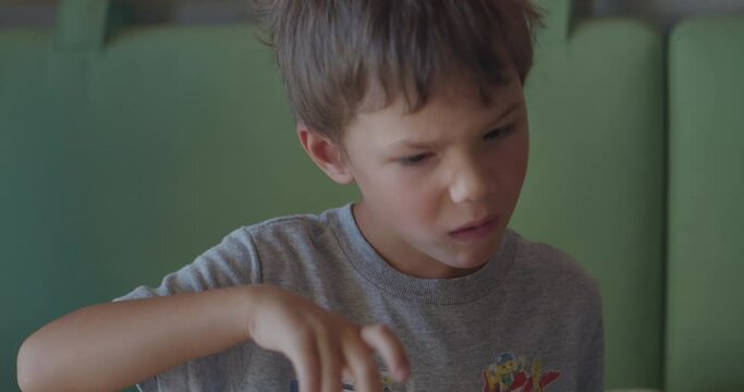 Funny boy in grey t-shirt chews bread Focaccia snack in cafe