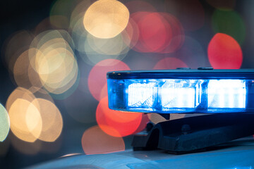 Blue lights on the roof of a police car with the background out of focus and lights with bokeh...