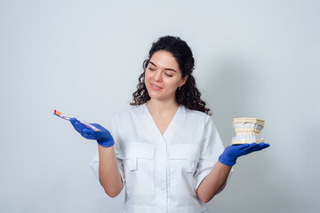 girl dentist holds a volumetric model of teeth and a toothbrush in her hands