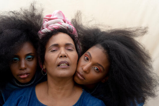 Portrait of black sisters leaning on aunt's shoulder