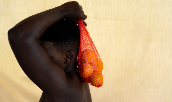 Young black man with sack of oranges