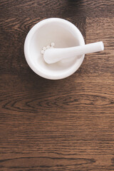 Tablets in a mortar being crushed with pestle for a compound; preparation of medication for a treatment