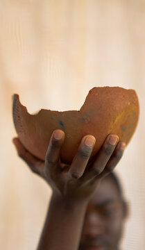 close-up on hand of a Young African Man holding calabash in front of studio beige background 