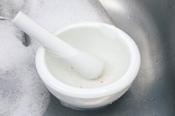 Mortar and pestle being cleaned in an aluminum sink; washing the mortar and pestle after use