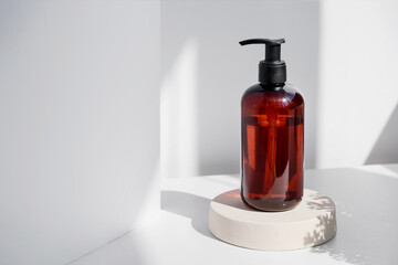 Brown glass bottle on white background in the morning rays of light. Eco cosmetic cream, serum for skin, face and body. Concept of skincare, spa and wellness center. Natural beauty products