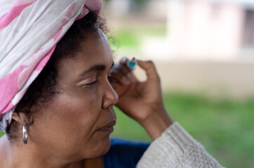 Obraz premium beautiful elderly woman in pink head wrap has her makeup done