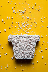 Perlite in a pot-shaped container on a yellow background, vertical image with copy space. Soil amendment and substrates for horticultural use concept.