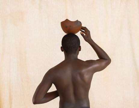 African Man holds calabash in front of studio beige background 