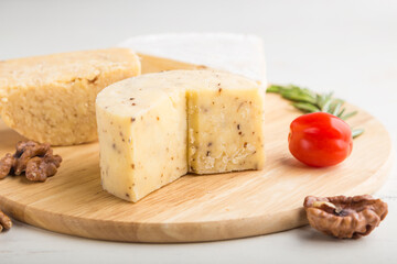 Cheddar and various types of cheese with rosemary and tomatoes on wooden board on a white background . Side view, selective focus.