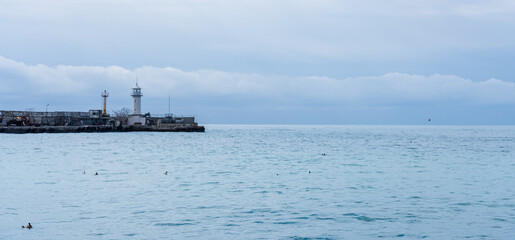 Sea panorama. Blue colors of the sky and the sea merge in color. A lighthouse is visible in the distance