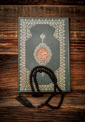 Holy Islamic Book Koran with rosary beads on wooden background. Quran with written arabic calligraphy meaning of Al Quran. Ramadan Mubarak. Ramadan kareem. 