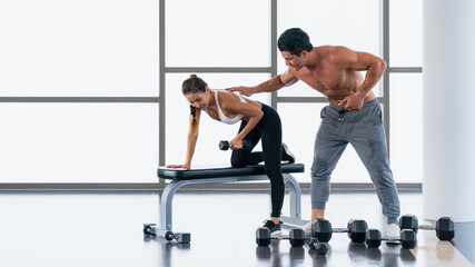 Fototapeta premium gym trainer coaching athletic woman workout with dumbbell lifting