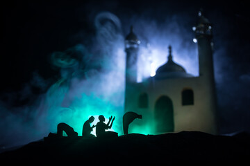 Naklejka na ściany i meble Silhouette of mosque building on toned foggy background. Ramadan Kareem background. Mosque at sunset. Praying people
