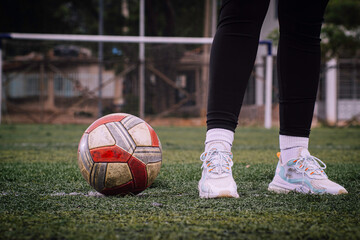 Woman standing inside a soccer field next to a ball