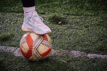 Close-up of a woman's foot stepping on a soccer ball.