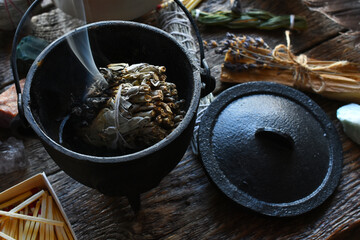 A close up image of a burning white sage smudge stick, healing crystals, and sacred feather. 
