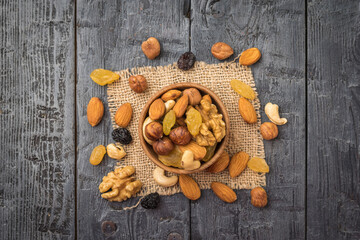 A mixture of nuts in a bowl on a piece of burlap on a wooden table.