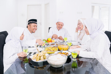 Obraz na płótnie Canvas Happy Muslim family having meals during Eid Mubarak