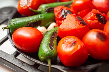 A closeup view of a salsa vegetable ingredients roasting on a comal.