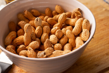 A view of a bowl of peanuts in their shells.