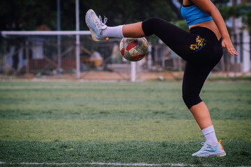 Woman doing series with soccer ball on synthetic turf