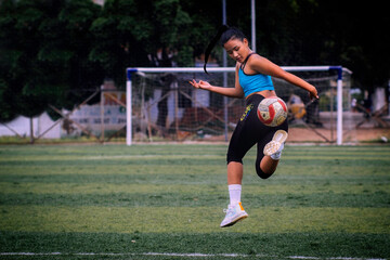 Woman doing series with soccer ball on synthetic turf