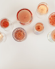 Rose wine assortment in crystal glasses, rose champagne sparkling wine on light background. Summer alcoholic drink