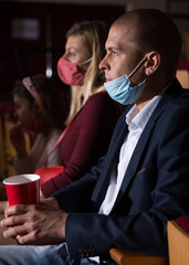 portrait of caucasian viewer sitting at premiere in theatrical hall during pandemic
