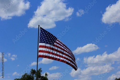 American flag against blue sky with clouds in Hutchinson Kansas USA.