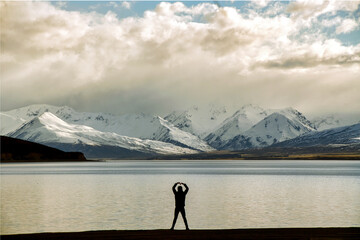 A man standing by the water And showing love gestures in Korean style And the background is Mount Cook, amazing nature at Lake Tekapo, New Zealand.