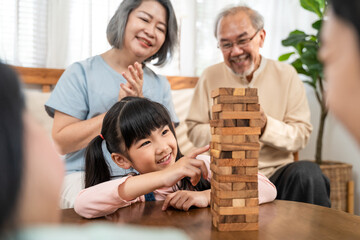 Close-up shot of Asian little girl playing Jenga game with family.