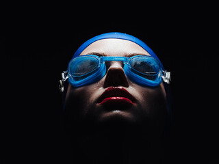 beautiful woman in goggles for swimming and bright makeup red lips black background