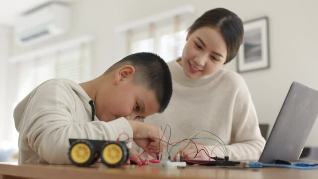 Young asia student remotely learn online at home with parent in coding robot car and electronic board cable in STEM, STEAM, mathematics engineer science technology computer code in robotics for kids.