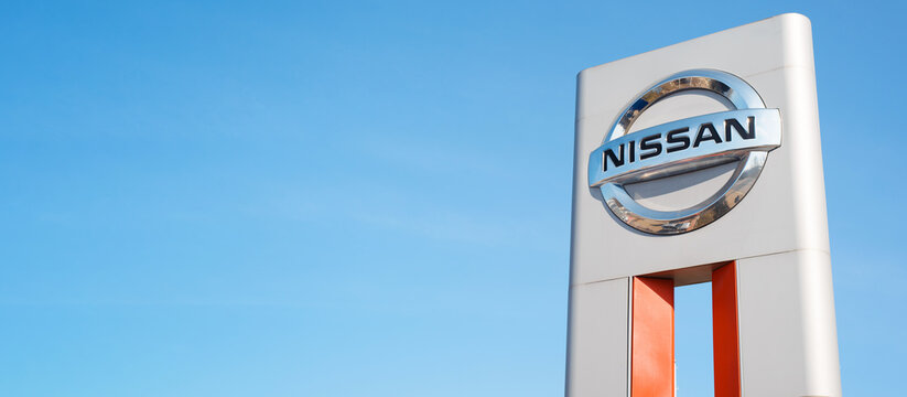 Nissan car manufacturer Japanese company logo, clear blue sky background outside. Banner, copy space, blank space for your text.