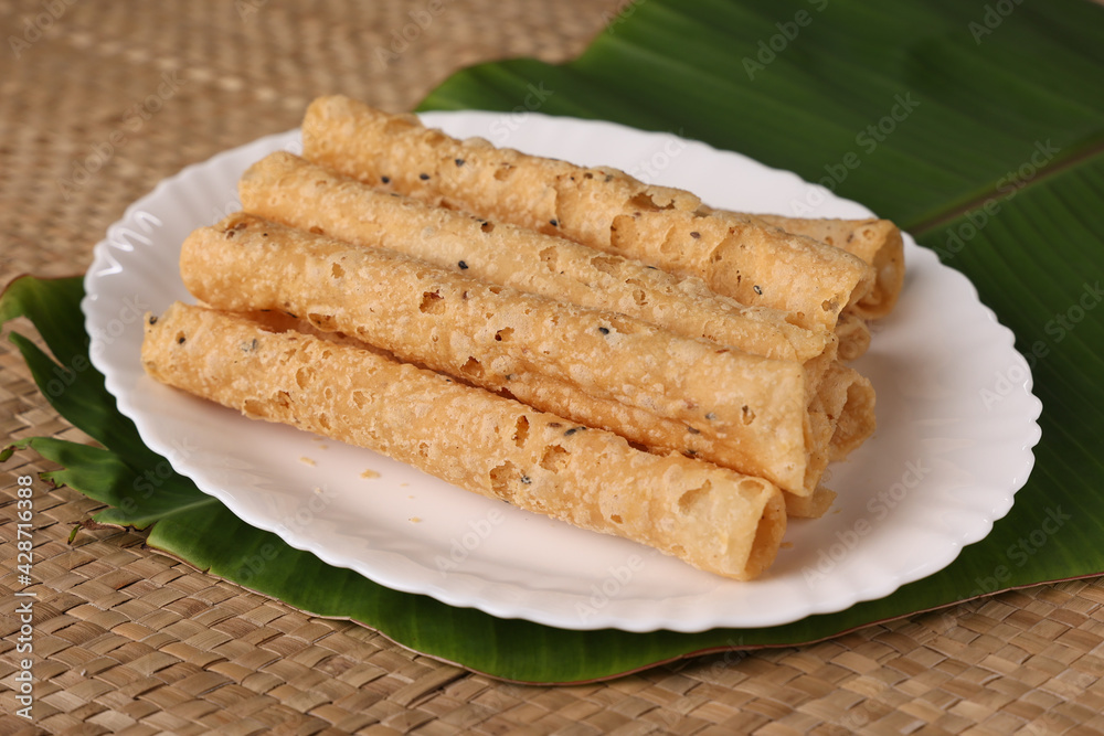 Wall mural Indian fried snack Kuzhalappam Kerala fried snacks food on banana leaf background. Kerala tea time food fried in coconut oil. Top view of South Indian snacks.	