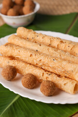 Indian fried snack Kuzhalappam Kerala fried snacks food on banana leaf background. Kerala tea time food fried in coconut oil. Top view of South Indian snacks.	