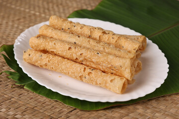 Indian fried snack Kuzhalappam Kerala fried snacks food on banana leaf background. Kerala tea time food fried in coconut oil. Top view of South Indian snacks.	