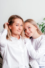 A mother and her teenage daughter are sitting on the couch at home, hugging each other and spending time together. Women's generation, International Women's Day, Happy Mother's Day.