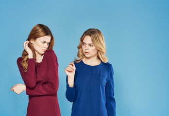 two girlfriends in dress conflict emotions blue background studio