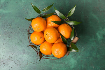 Basket with sweet tangerines on color background