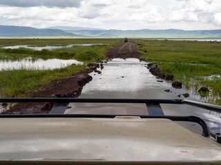 Ngorongoro Crater, Tanzania, Africa - March 1, 2020: Crossing flooded roads in jeep