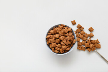 Bowl with tasty corn pillows on light background
