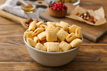 Bowl with tasty corn pillows on wooden background