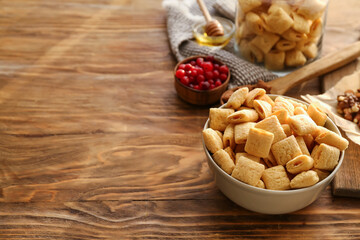 Bowl with tasty corn pillows on wooden background