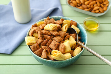 Bowl with tasty corn pillows and bottle of milk on color wooden background
