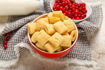 Bowl with tasty corn pillows and cranberries on light background