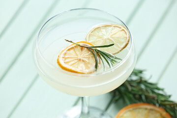 Glass of cocktail with rosemary and dried citrus fruits on color wooden background